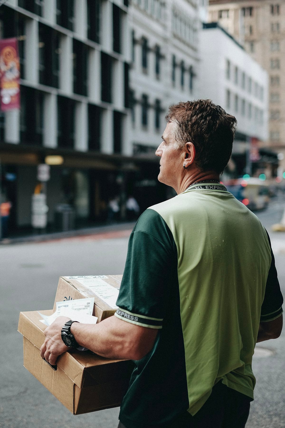 Courier carrying a parcel along a busy city street