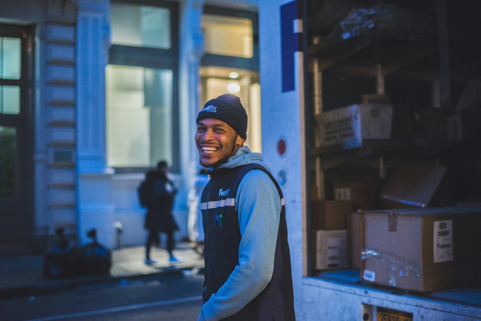 Smiling Priority Parcels courier standing next to a loaded delivery van