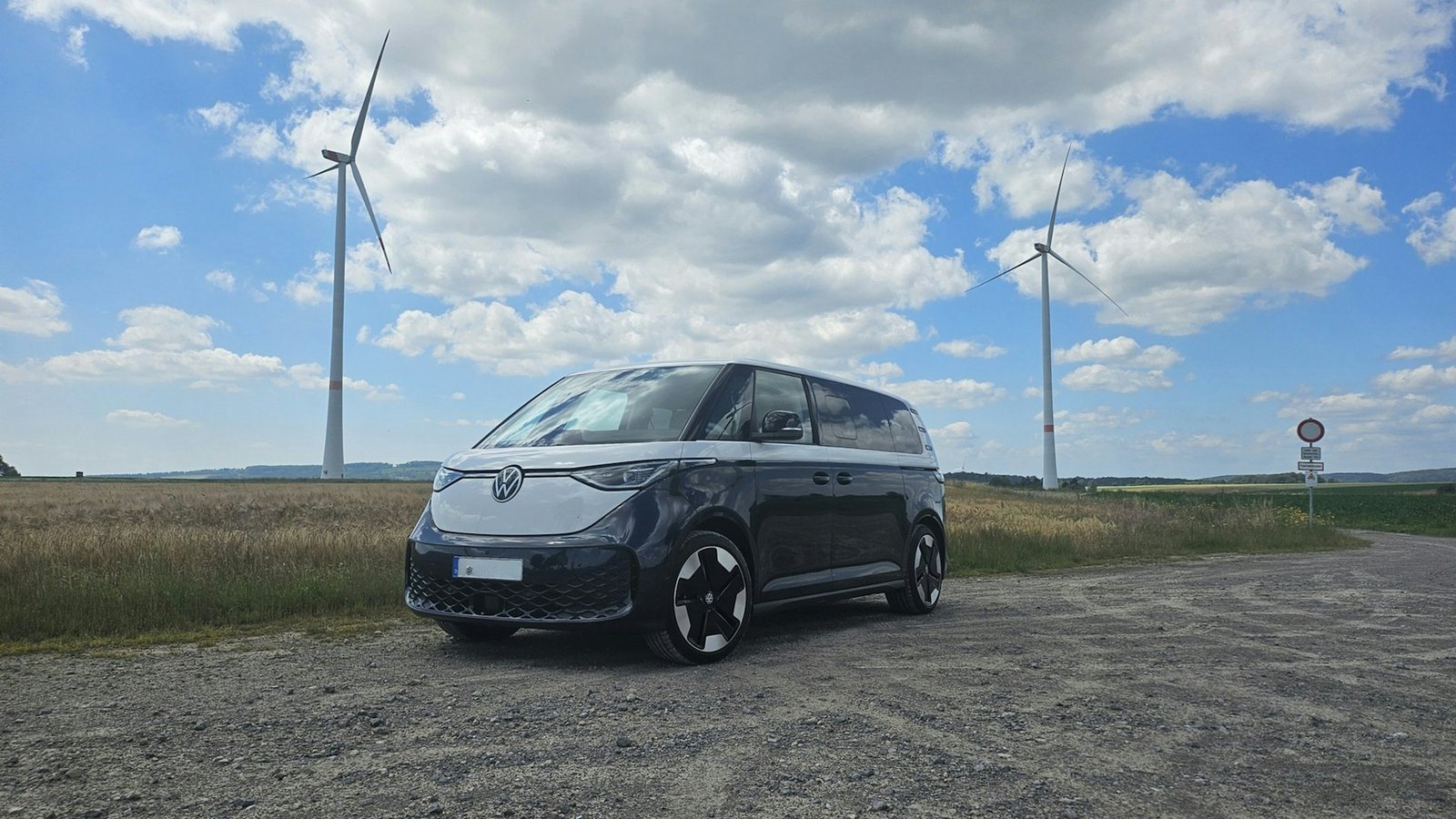 Electric delivery van parked in front of wind turbines